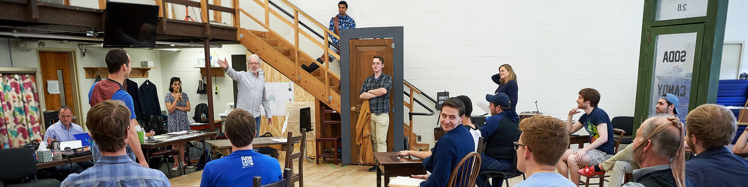 UConn Drama students seated around a professor in a de-constructed set of door-frame props