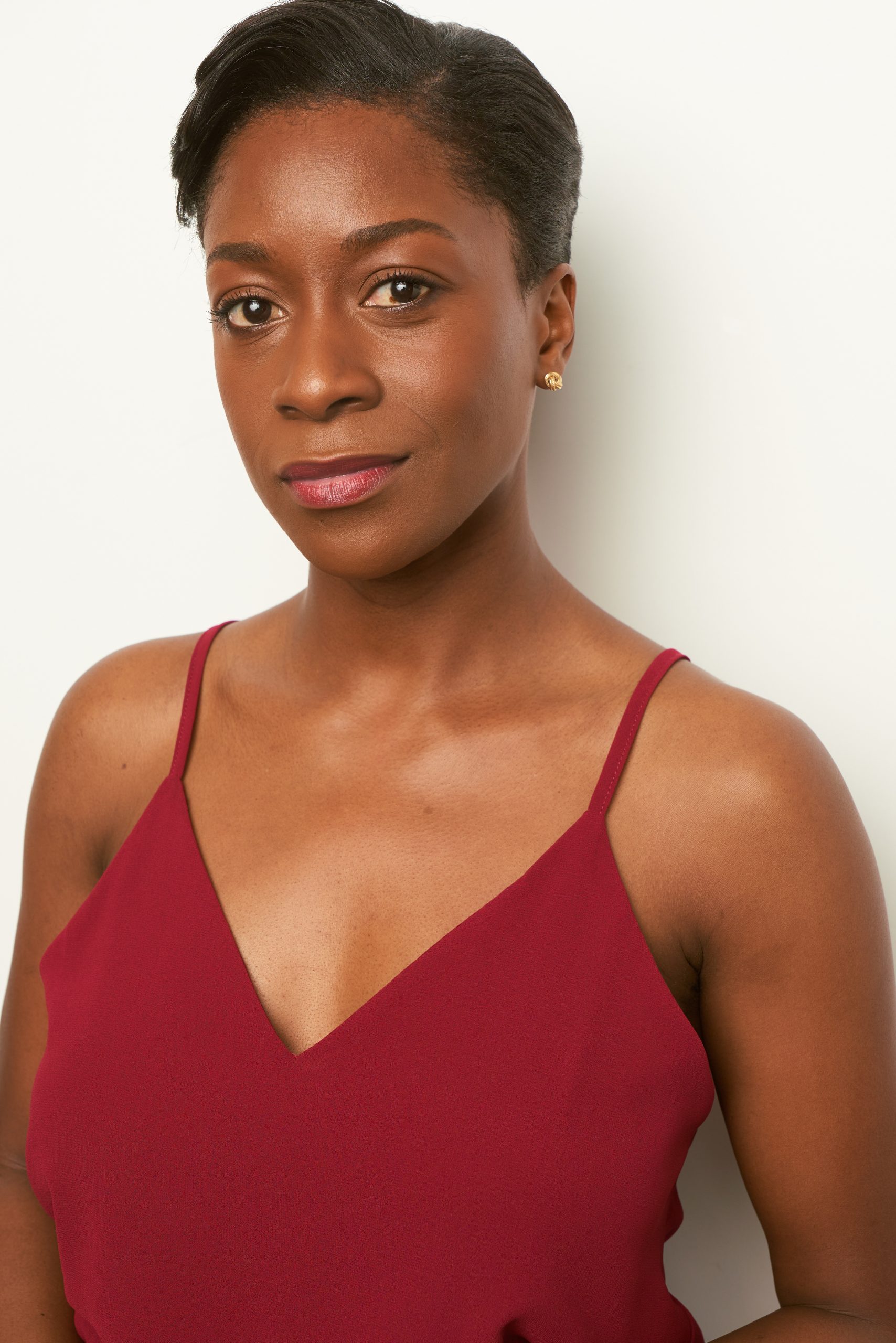 Woman with short haircut smirking wearing red shirt