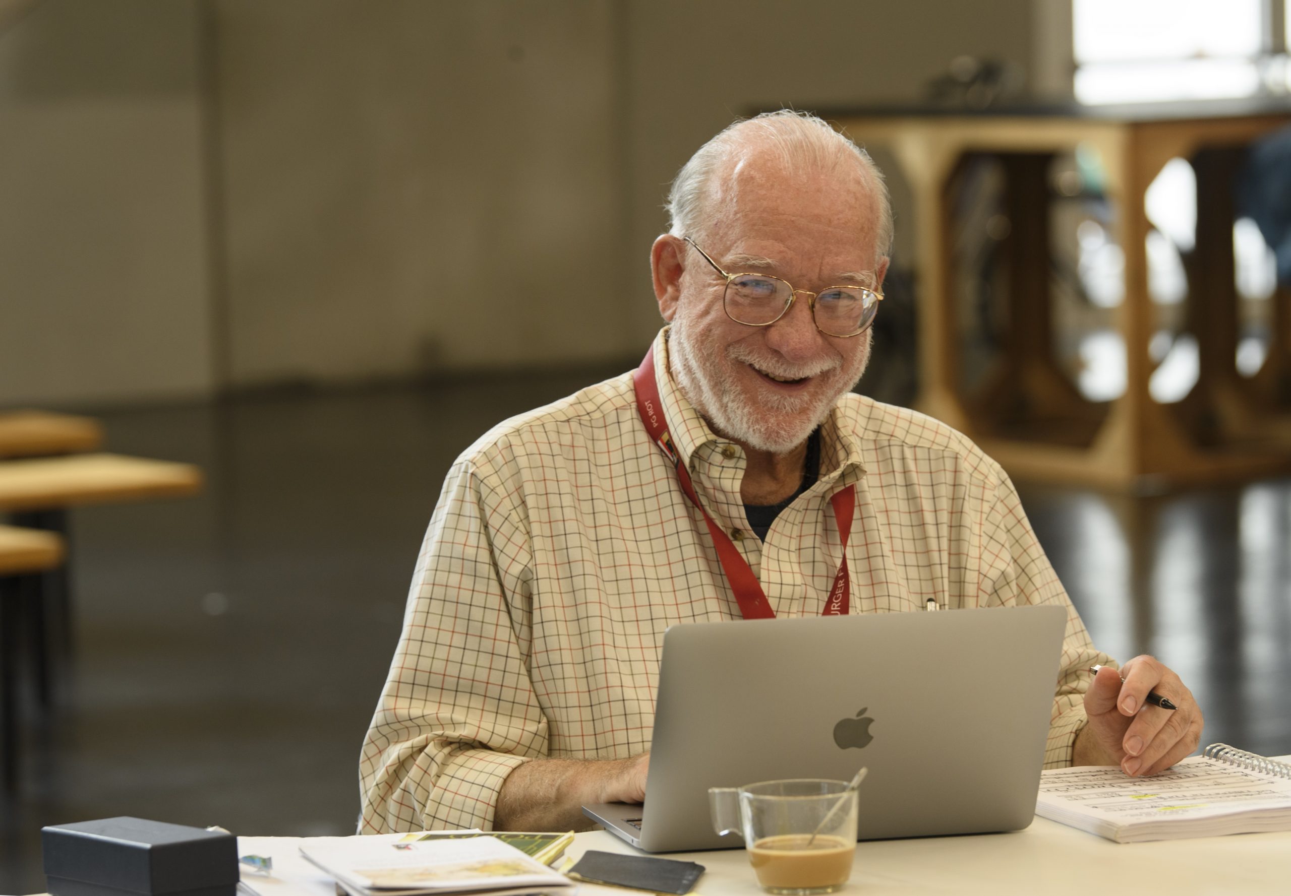 Bald man with glasses smiling, looking at laptop