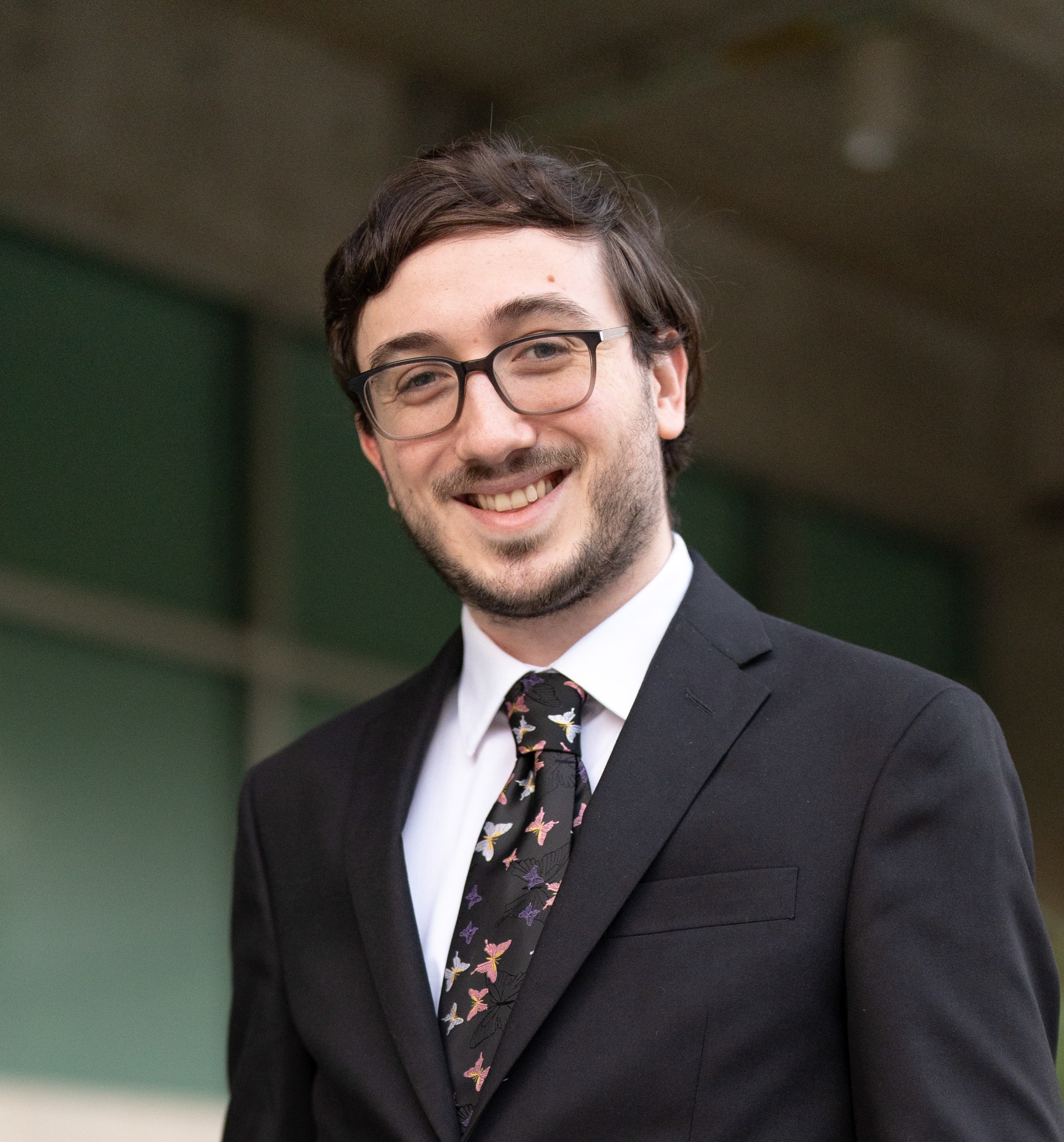 Man with glasses in black suit smiling 
